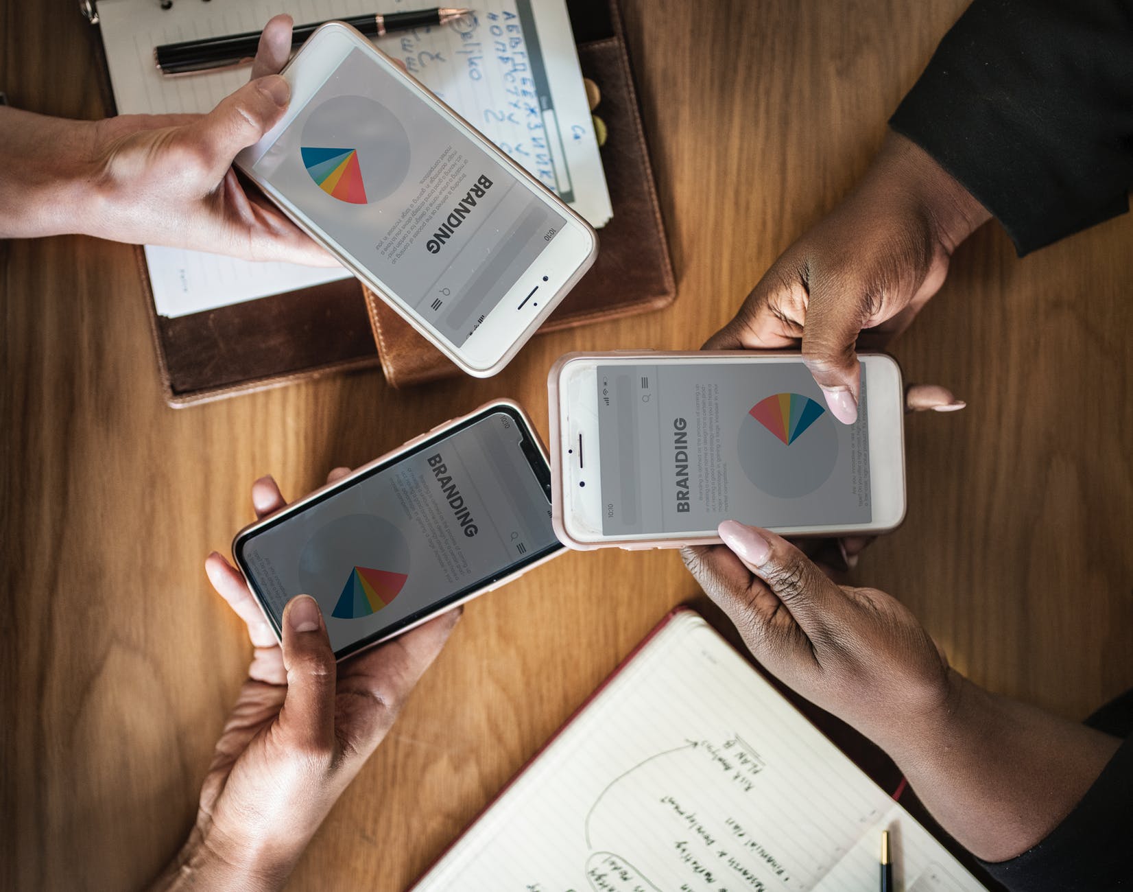 three people holding phone displaying branding pie chart